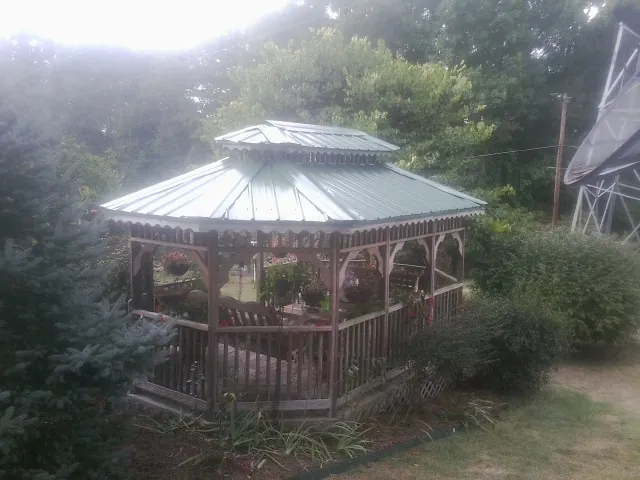 Green metal roof on a backyard gazebo surrounded by garden beds in Hamilton