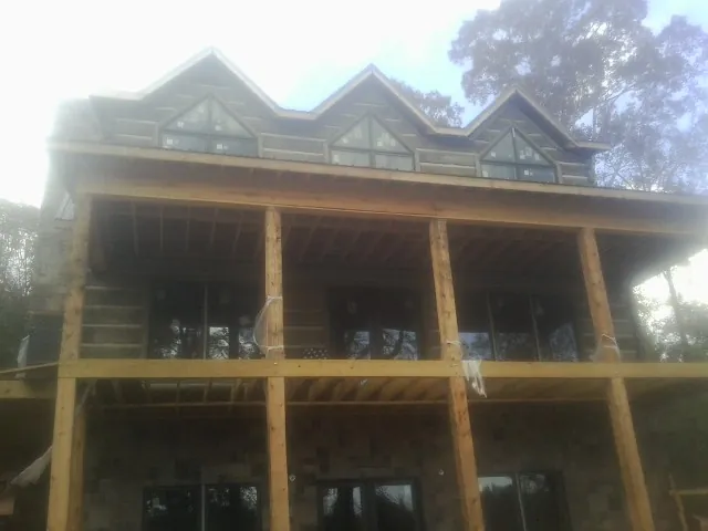 Dormers and porch framing on a large log home under construction — Roof Coating work by our crew in Hamilton